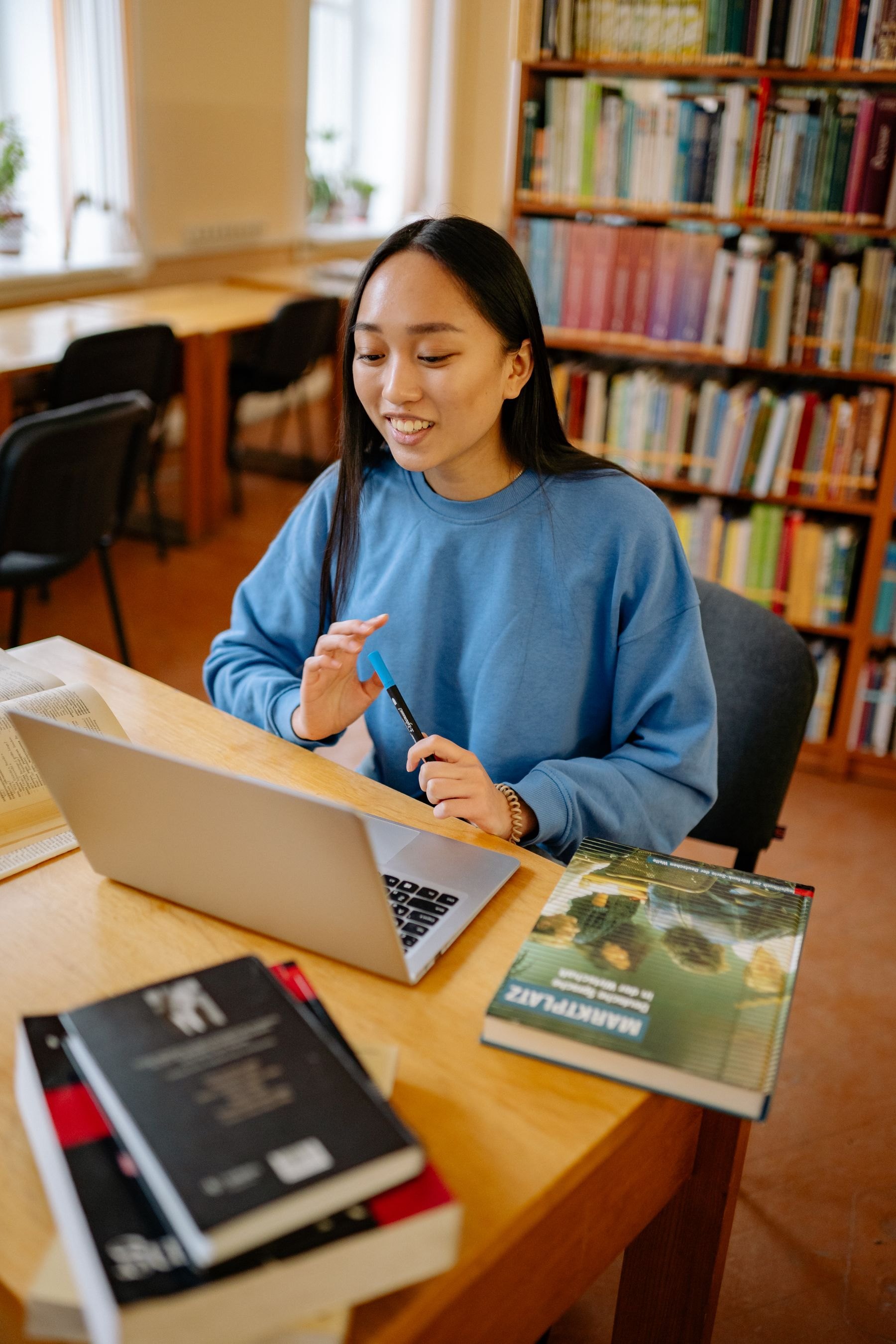 Colaboradora trabajando con un portátil y un libro de idiomas en una biblioteca