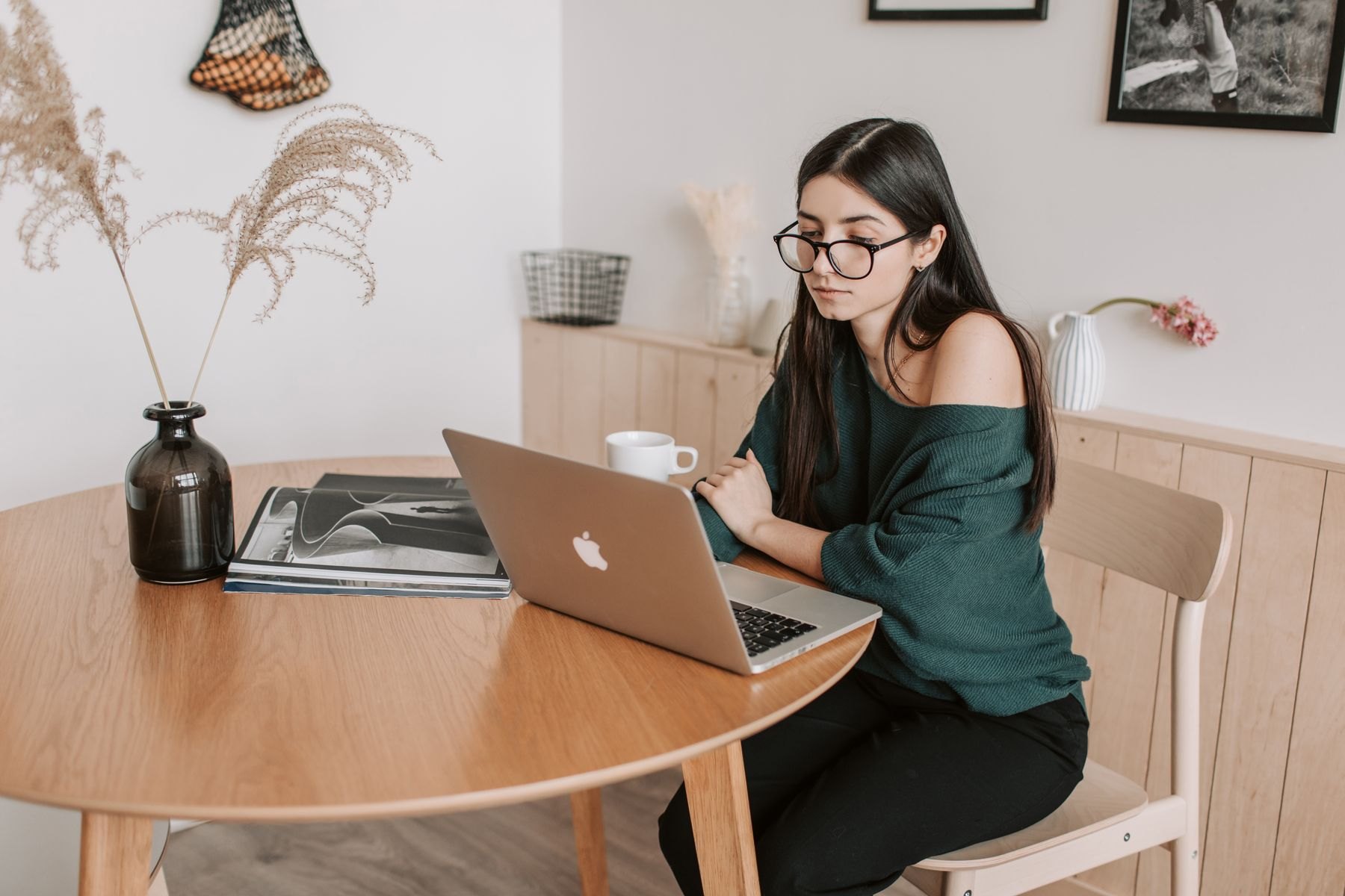 Revisora con gafas concentrada en un portátil en casa