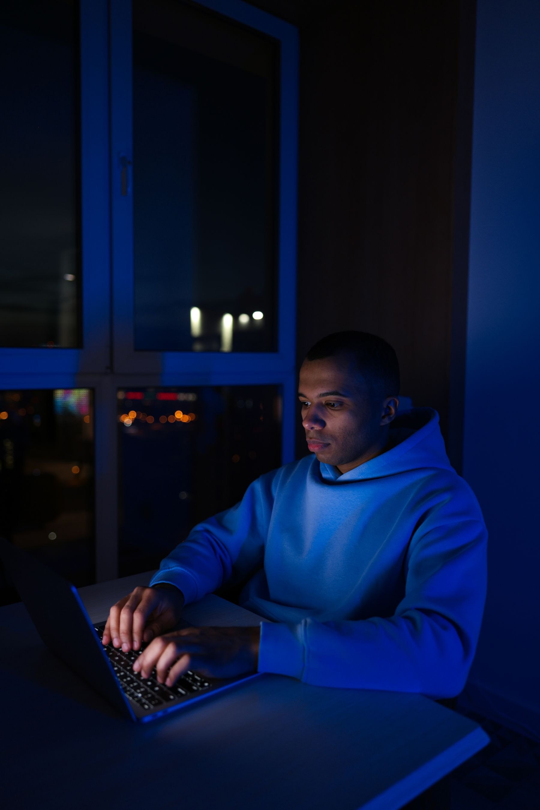 Colaborador escribiendo en un portátil de noche